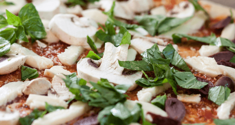An assortment of pizza toppings including mushrooms, leaves and tomato sauce.