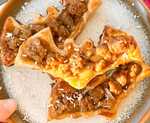 A hand holds a plate of apple crumble bats, showcasing a delicious dessert ready to be enjoyed.