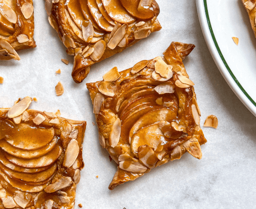 An enticing apple tart adorned with caramelized almonds, featuring a flaky crust and a sweet, aromatic apple filling.