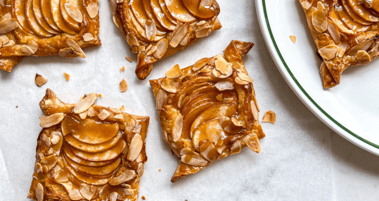 An enticing apple tart adorned with caramelized almonds, featuring a flaky crust and a sweet, aromatic apple filling.