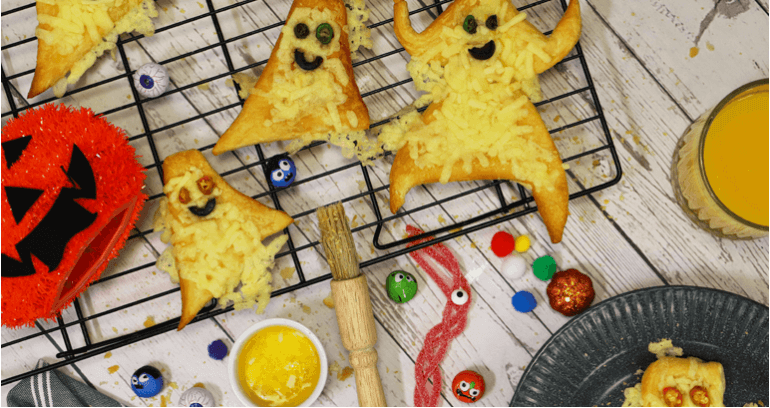 Cheesy Halloween ghost-shaped pastries arranged on a plate, perfect for festive celebrations and spooky treats.