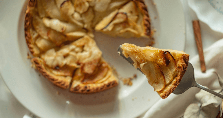 An inviting apple tart sprinkled with cinnamon, featuring a flaky crust and a rich, aromatic apple filling.