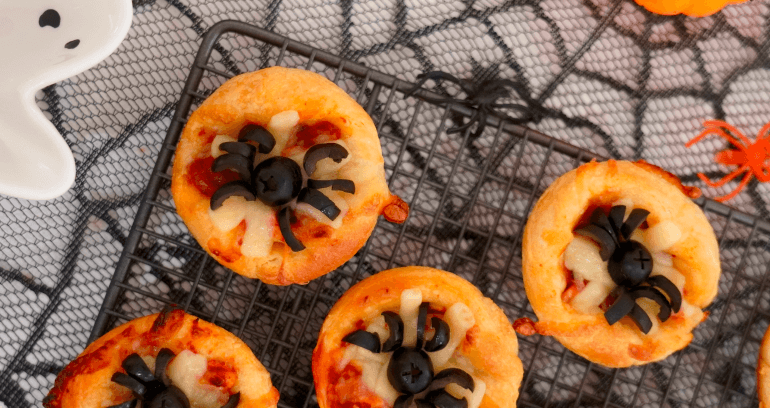 Halloween - themed pizza bites topped with black olives and melted cheese, perfect for festive gatherings.