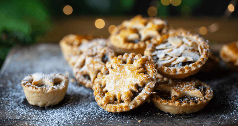 An assortment of mince pies served on a board dusted with icing sugar, ready to be enjoyed.