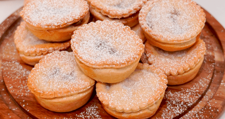 mince pies sprinkled with caster sugar served in a wooden plate