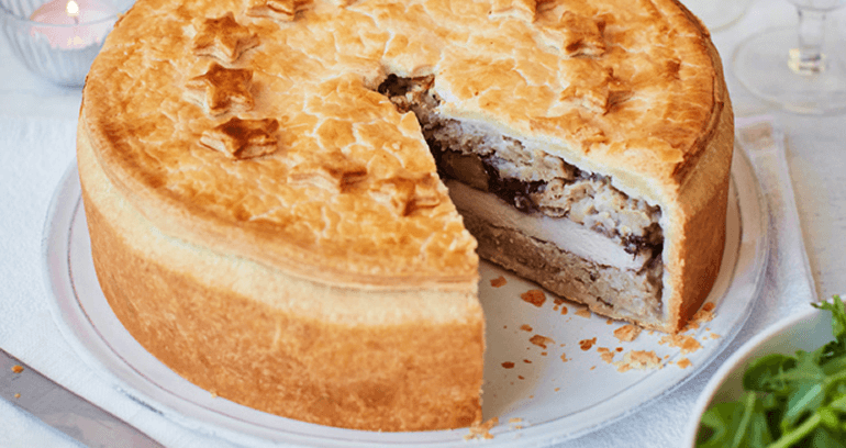 Christmas Dinner pie served on a white plate with one piece cut out.